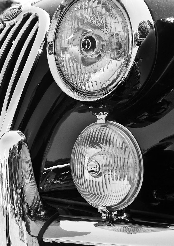 Chrome headlamps of a classic Jaguar in black and white