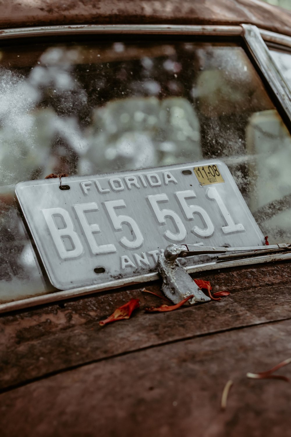 A weathered vintage Florida license plate still bolted to a rusting car